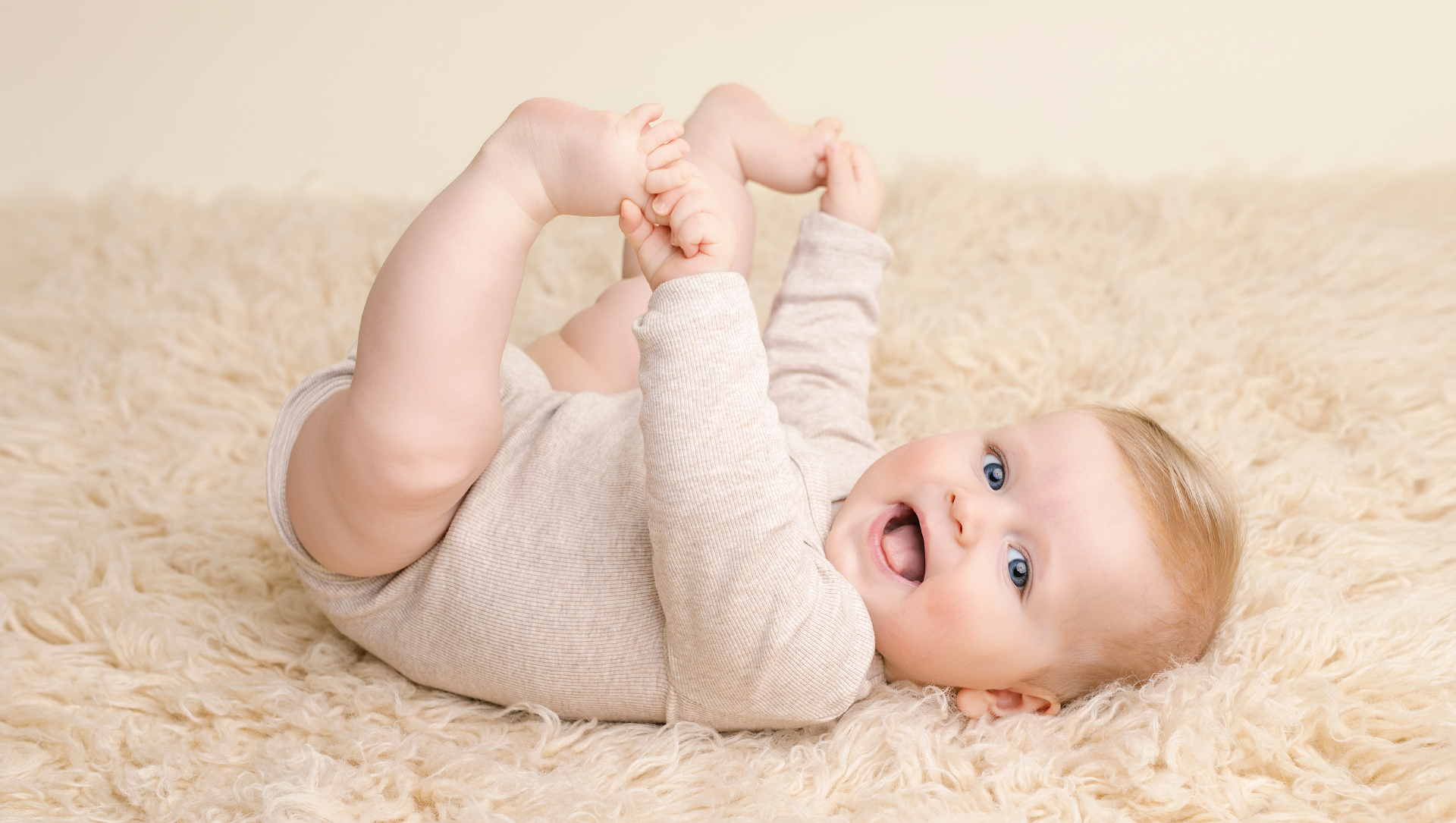 baby ligt op rug en pakt zijn voetjes vast tijdens fotoshoot in rotterdam